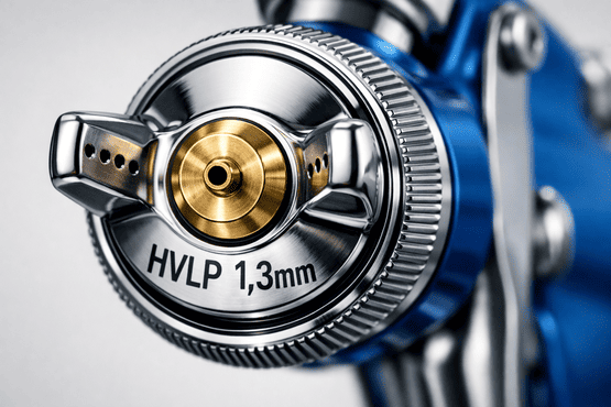 Makroaufnahme der verchromten Luftkappe einer HVLP Lackierpistole, auf der die Gravur HVLP und 1,3mm deutlich lesbar ist, mit Fokus auf der goldenen Messingdüse in der Mitte.