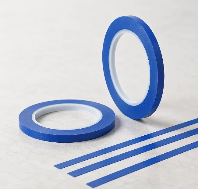 Zwei blaue Rollen Fineline-Tape liegen neben mehreren schmalen blauen Klebestreifen auf einer hellen Oberfläche.